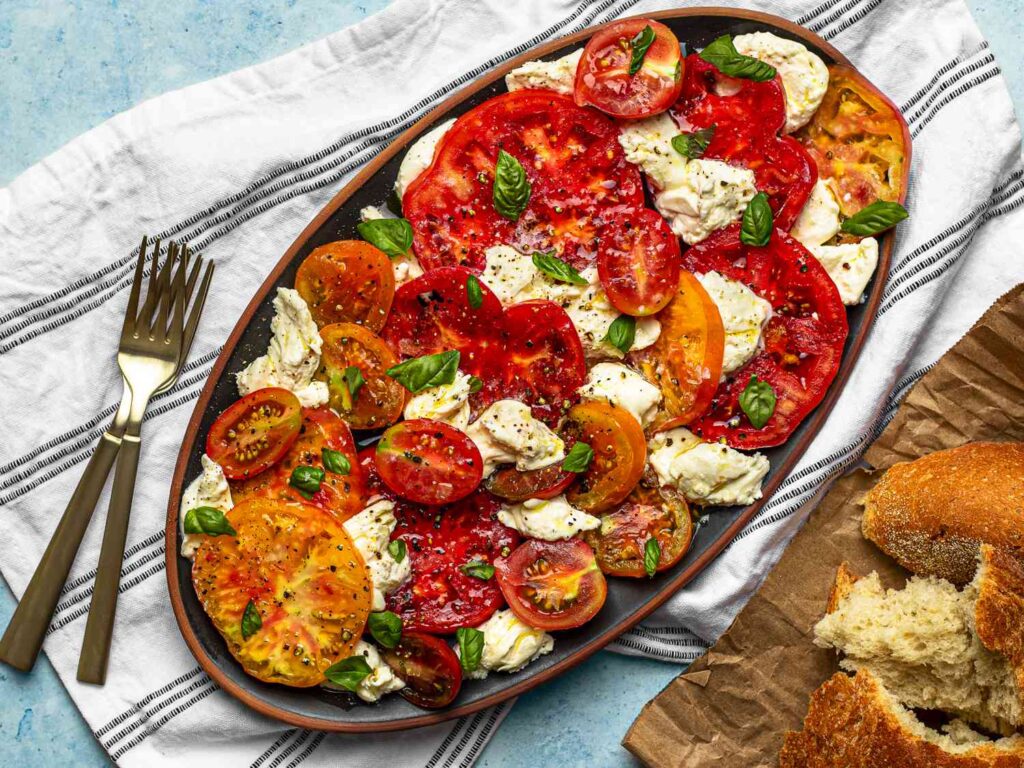 Italian vegetarian antipasto recipes Caprese Salad with ripe tomatoes, fresh mozzarella, and basil leaves